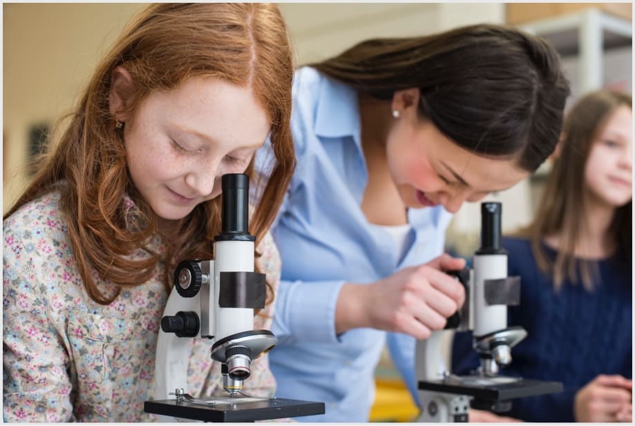 Teacher and student looking into microscope